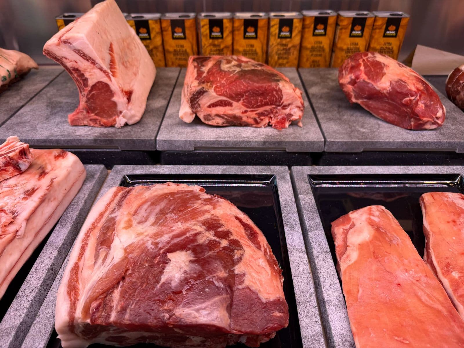 Des pièces de viande entières posées sur les plateaux de pierre de la vitrine, prêtes à être coupées